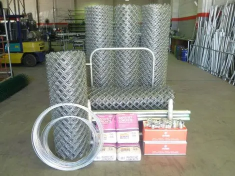 Chain-wire fencing DIY kit with mesh rolls, gate frame, tie wire, rapid-set concrete and fittings in a factory